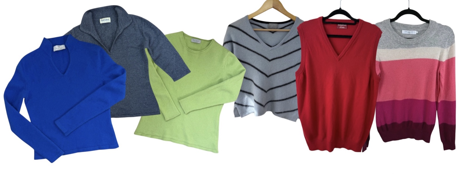 Six cashmere jumpers laid flat: cobalt blue, grey half zip, lime green, grey chevron, red V-neck and pink colour block
