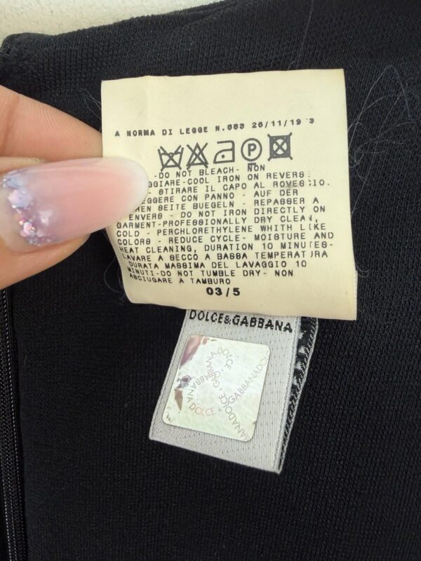 Care tag citing law n. 883 of 1973 and a holographic Dolce & Gabbana tag