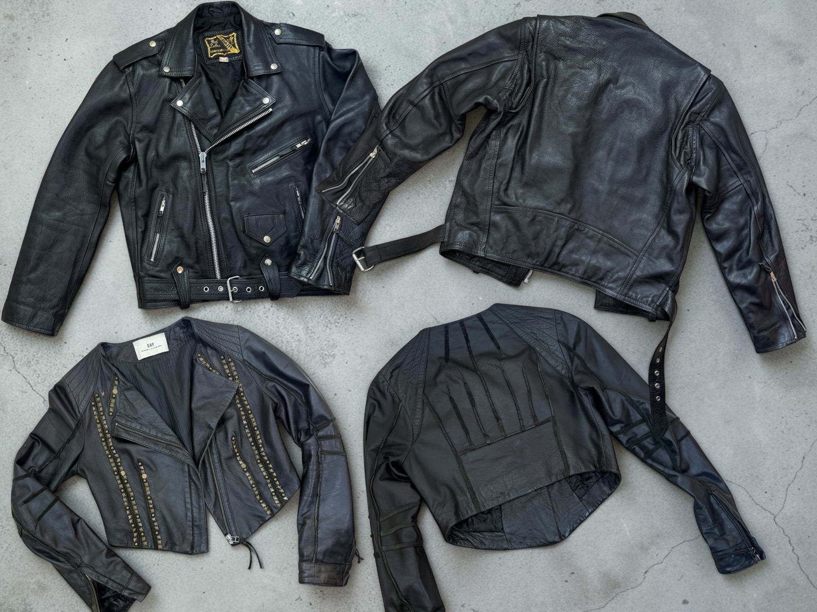 Two black leather biker jackets laid flat, front and back: a classic one with an off-centre zip, snap-down lapels and belt, and a cropped studded one