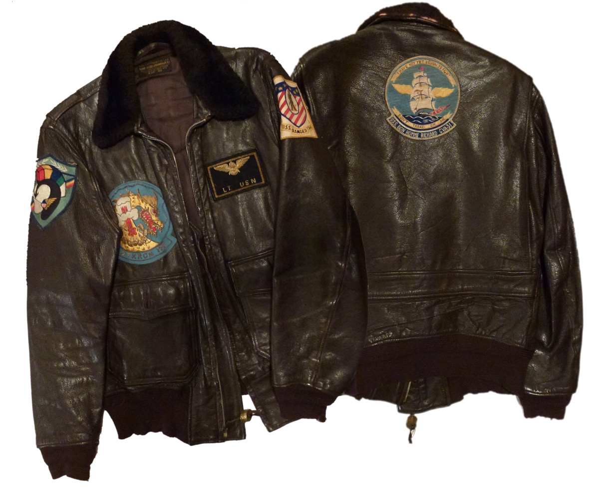 A dark brown leather US Navy G-1 flight jacket with a fur collar and squadron patches, shown from the front and the back